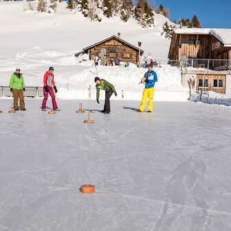 Curling auf dem Natureisfeld der Berghütte Alp Raguta