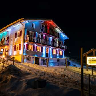 Das Gasthaus Alpina beleuchtet im Winter am Abend